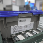 Blue plastic tote with RFID tag on a conveyor belt